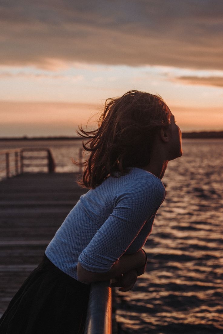 Frau bei Sonnenuntergang am Steg